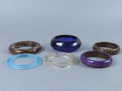 Plusieurs bracelets de différentes couleurs sont disposés sur une surface blanche.