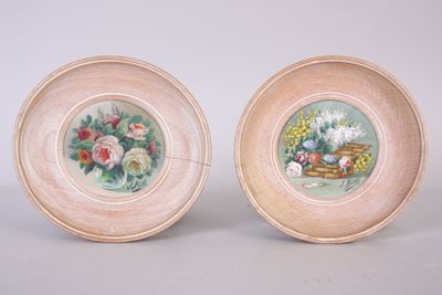two plates with flowers painted on them sitting next to each other