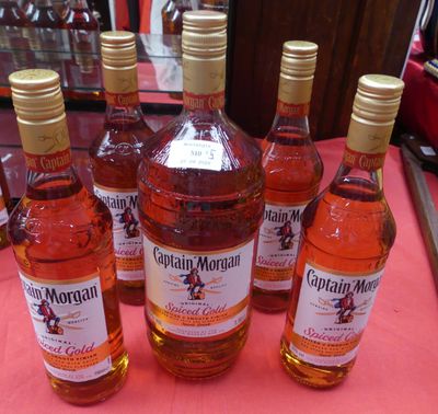 six bouteilles d'alcool sont alignées sur une nappe rose