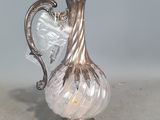 un vase en argent et en verre muni d'une anse, posé sur une table
