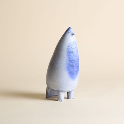 un petit objet bleu et blanc posé sur une surface blanche