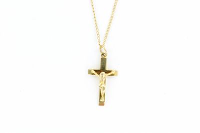 un pendentif en forme de croix en or, suspendu à une chaîne, sur fond blanc