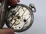 a person holding a silver pocket watch in their hand