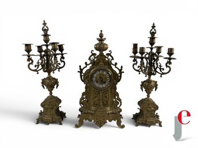 three candles and a clock sitting on a table