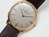 gros plan d'une montre sur une surface blanche avec un bracelet marron