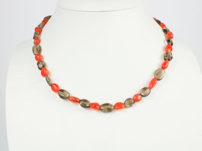 un collier composé de perles rouges et vertes sur un mannequin blanc