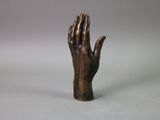 statue of a hand holding something in the air on a gray background