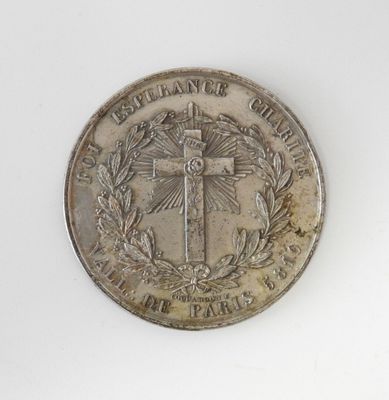 une pièce d'argent sur laquelle est gravée une croix, sur un fond blanc