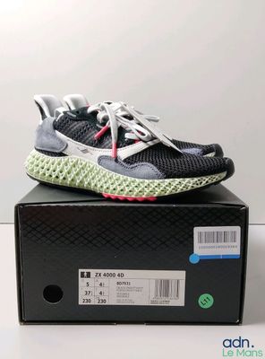 une paire de chaussures de course noires et blanches posée sur une boîte