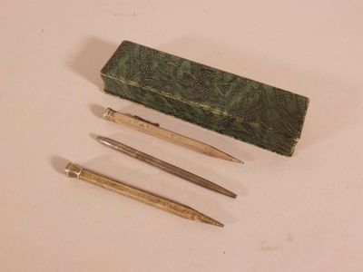 trois stylos et un crayon dans une boîte posée sur une table