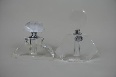 une paire de flacons de parfum en verre transparent posés sur une surface blanche