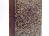 un vieux livre à la couverture brune posé sur une surface blanche