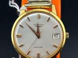 a gold wrist watch with a white face on an orange bracelet