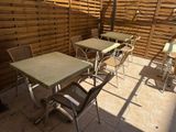 tables and chairs on a patio with a wooden fence in the background