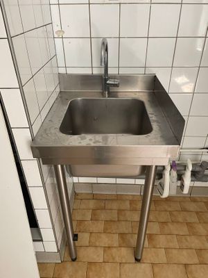 un évier en acier inoxydable dans le coin d'une salle de bains