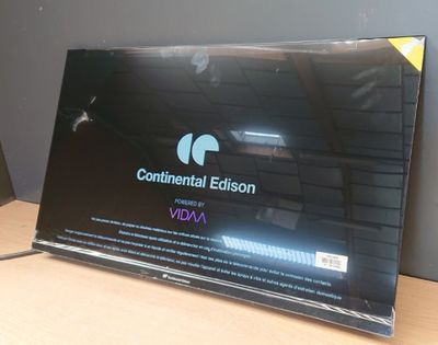 un ordinateur portable posé sur un bureau, sur lequel est posée une pancarte
