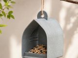 un gros plan d'une mangeoire à oiseaux suspendue à une branche d'arbre