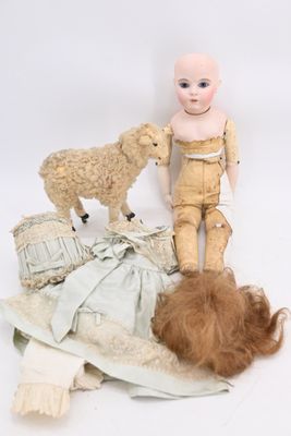 a doll and a sheep on the ground next to a pile of clothes