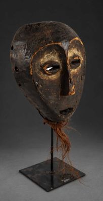 a wooden mask on a stand with a black background