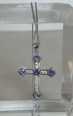un pendentif en forme de croix bleue et blanche présenté dans un écrin transparent