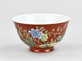 an orange bowl with blue flowers on it sitting on a white surface