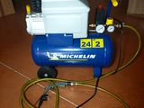 a blue air compressor sitting on the floor with a hose
