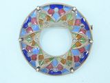 a close up of a colorful broochle on a white surface