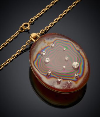 un gros plan d'un collier posé sur une surface noire, avec une chaîne dorée