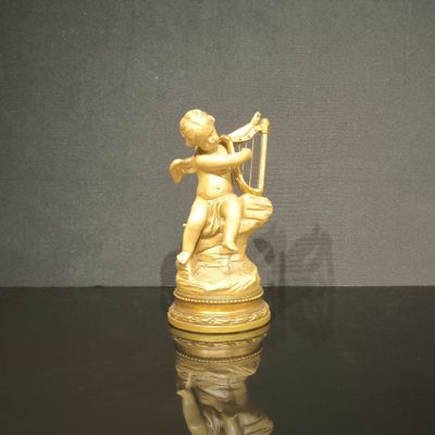 figurine en or représentant un Cupidon jouant de la harpe sur un fond noir