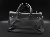 a black leather bag sitting on top of a black surface