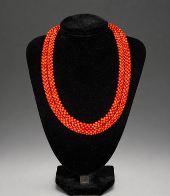 an orange beaded necklace on a black mannequin