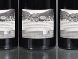 three bottles of wine sitting on top of a table next to each other