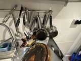 Dans une cuisine, des casseroles et des poêles sont accrochées au mur