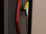a black refrigerator with a red handle and a yellow sticker on the door