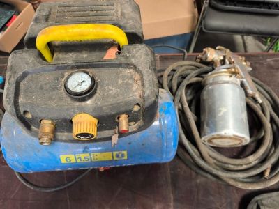 un compresseur d'air bleu posé sur une table à côté d'autres outils