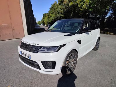 un Range Rover blanc garé sur un parking à côté d'un immeuble