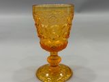 yellow glass goblet on a white table with a gray background