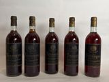 six bottles of wine are lined up on a white surface