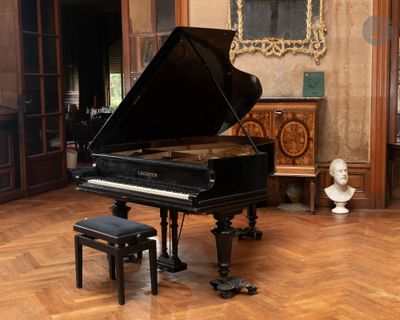 un piano à queue au milieu d'une pièce, avec le buste d'un homme en arrière-plan