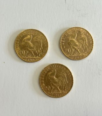 three gold coins sitting on top of a white surface next to each other