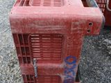 a red crate sitting on the ground next to a red cart