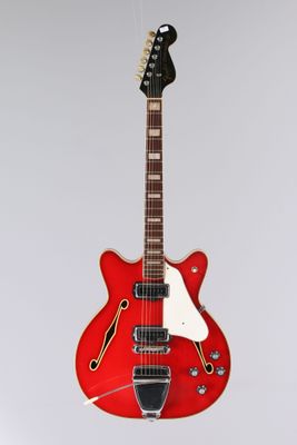 une guitare électrique rouge suspendue à une ficelle sur un mur blanc