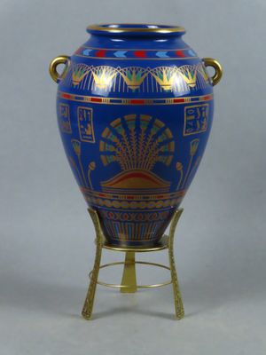 un vase bleu posé sur un socle, muni d'une anse dorée