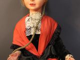 a doll that is wearing a red and black dress