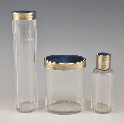 trois récipients en verre transparent ornés de bordures dorées et dotés d'un couvercle bleu