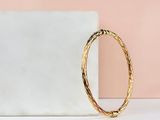 a gold bang bracelet sitting on top of a marble block