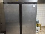 stainless steel double door refrigerator in a commercial kitchen with tile flooring