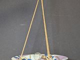 a close up of a bowl hanging from a rope on a wall
