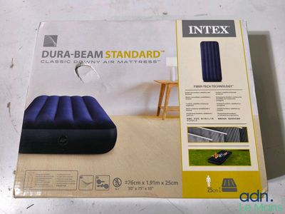 La boîte du matelas gonflable est ouverte et le matelas est prêt à l'emploi.