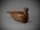 an old wooden duck sitting on top of a gray surface